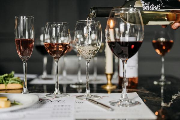 White wine pouring into a wine glass on a table, with other wine glasses full of different wine surrounding it.