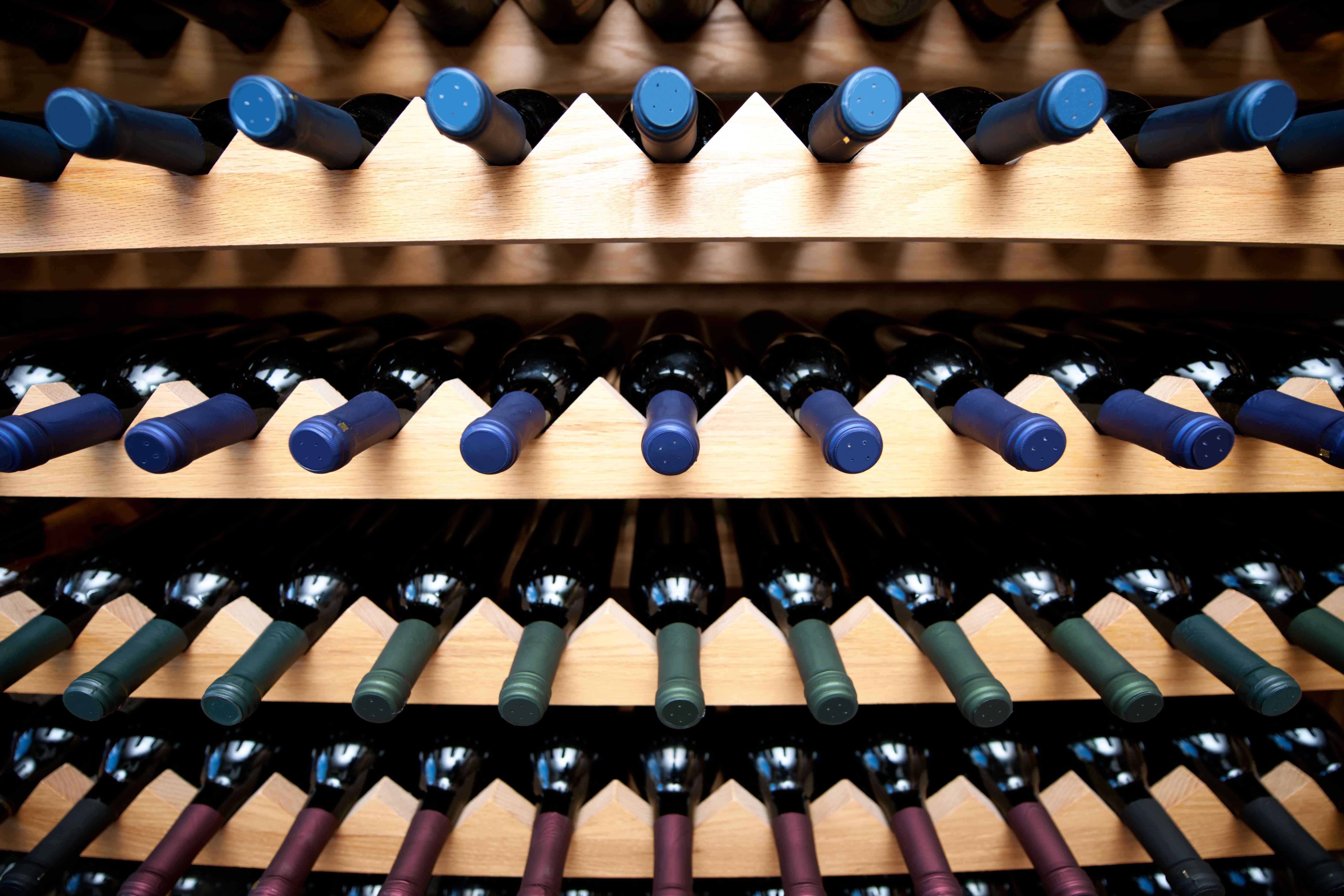 Wine bottles stored horizontally in a wooden diamond bin wine rack.