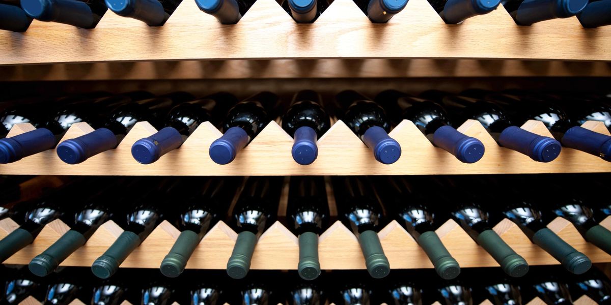 Wine bottles stored horizontally in a wooden diamond bin wine rack.