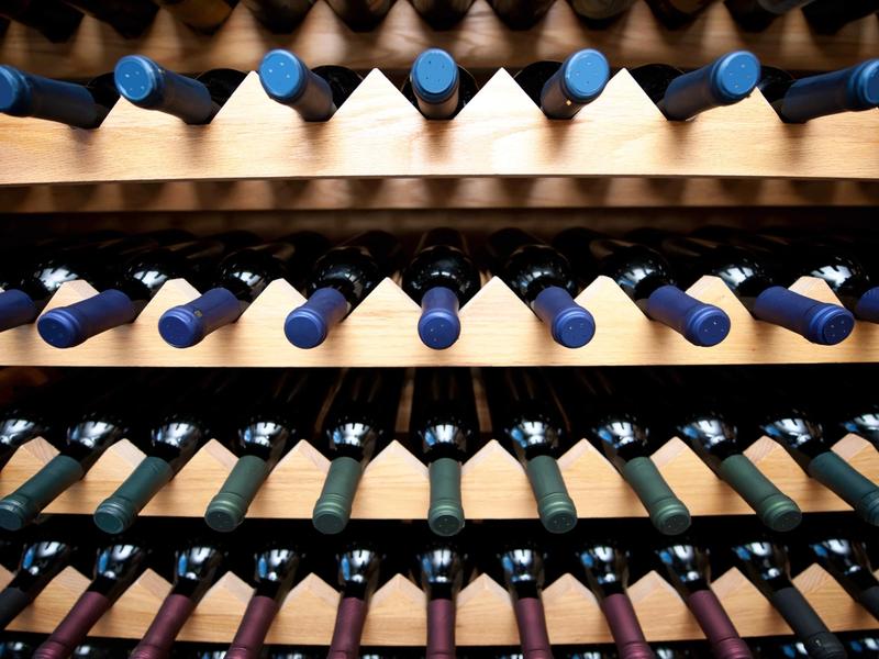 Wine bottles stored horizontally in a wooden diamond bin wine rack.