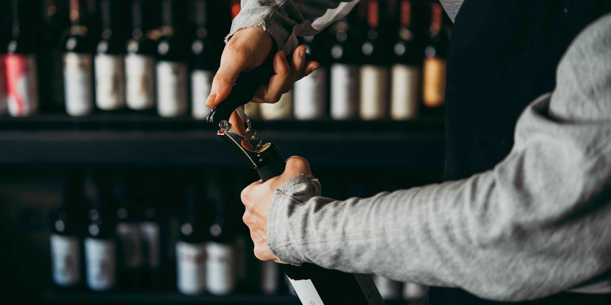 A waiter opening a wine bottle at a restaurant.