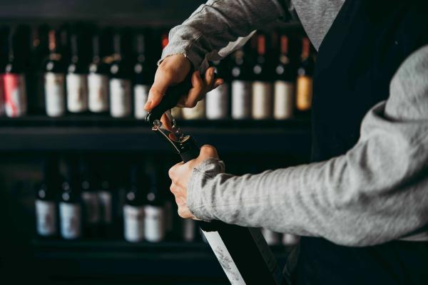 A waiter opening a wine bottle at a restaurant.