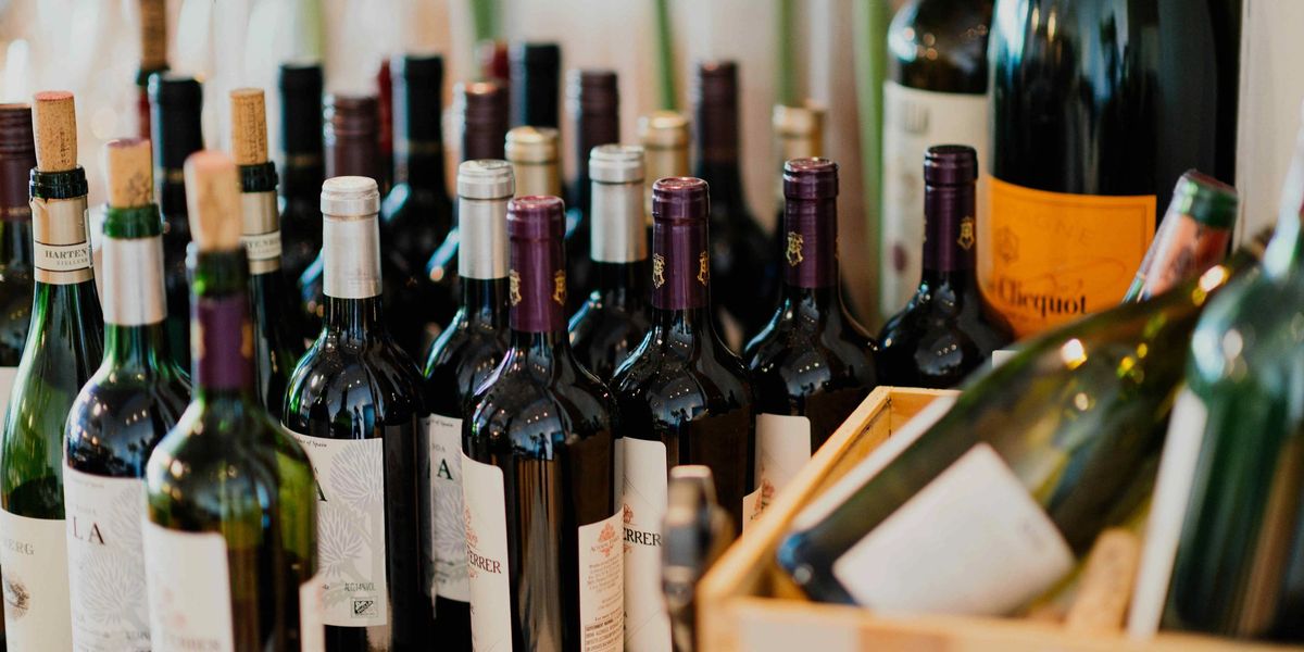 Assortment of wine bottles with different capsules and labels clustered together on a table.