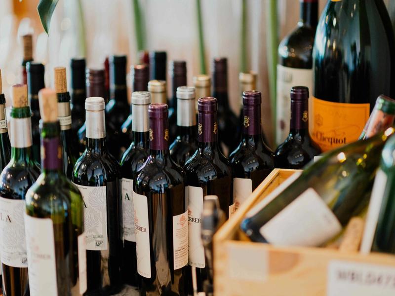 Assortment of wine bottles with different capsules and labels clustered together on a table.