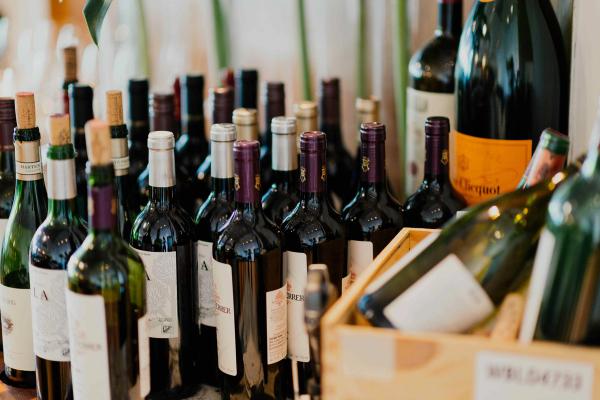 Assortment of wine bottles with different capsules and labels clustered together on a table.