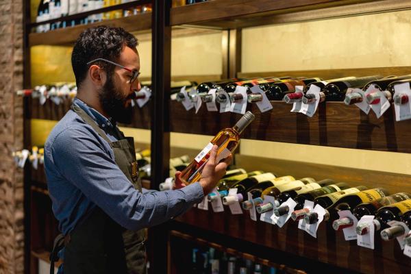 A sommelier analyzing the label of a wine bottle in a restaurant's wine cellar.