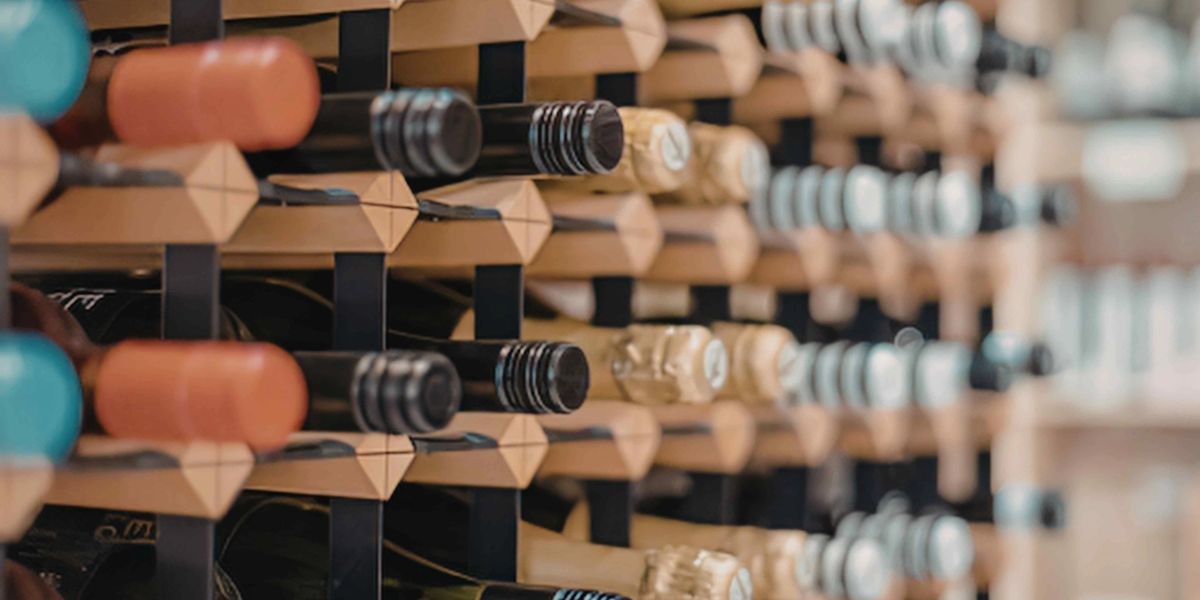 Rows of wine bottles stored horizontally on a wooden rack, viewed at an angle.