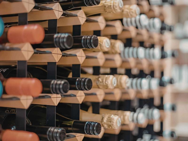 Rows of wine bottles stored horizontally on a wooden rack, viewed at an angle.