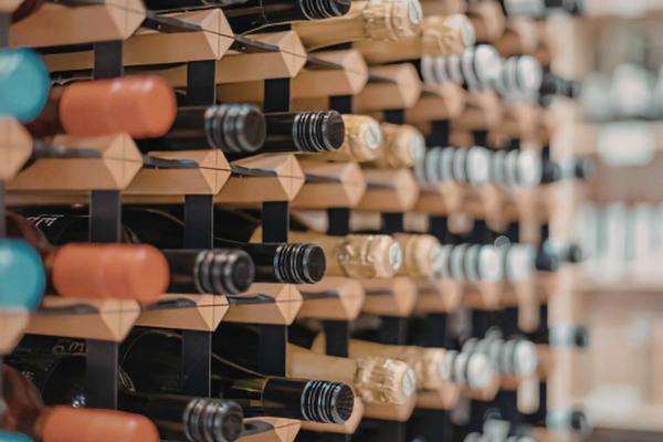 Rows of wine bottles stored horizontally on a wooden rack, viewed at an angle.