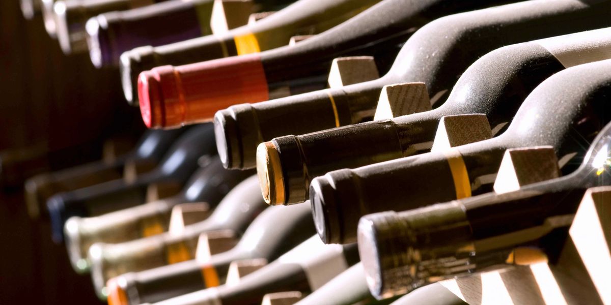 Row of wine bottles resting on their sides in a rack, viewed at a low angle.