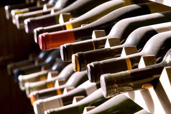 Row of wine bottles resting on their sides in a rack, viewed at a low angle.