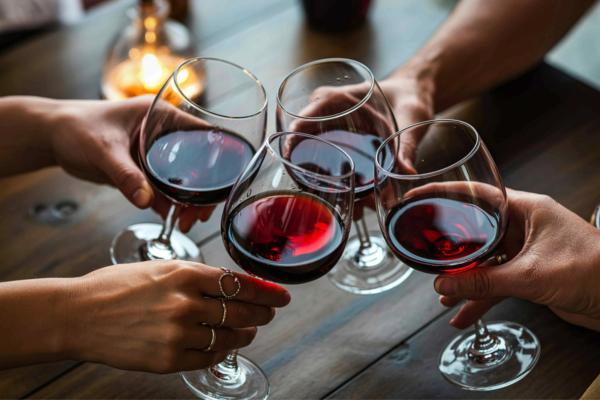 Four clinking glasses of red wine at a restaurant.