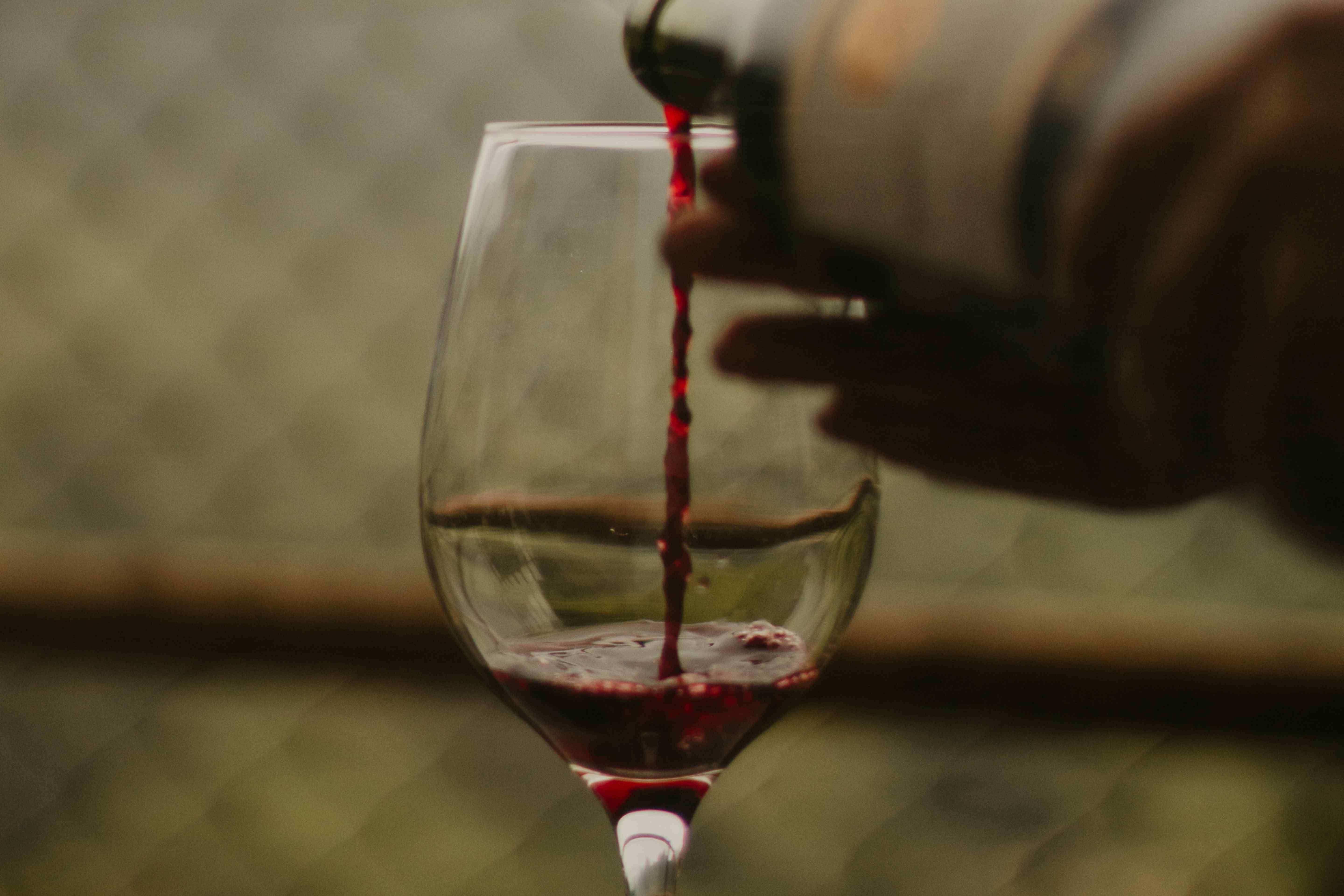 Red wine being poured into a glass, already partially filled.
