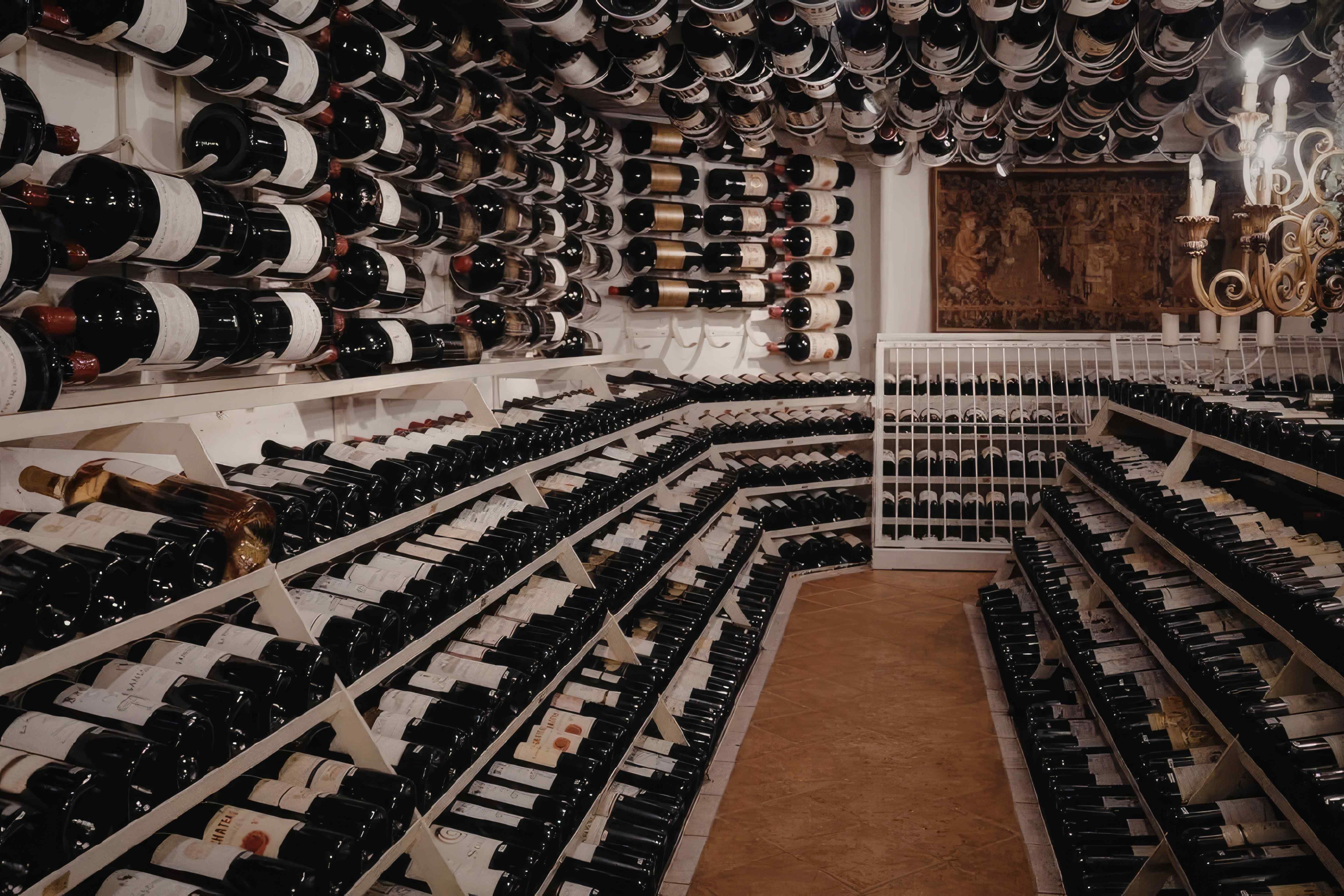 A very large wine cellar, with rows full of wine bottles and large display bottles on the walls and ceiling.