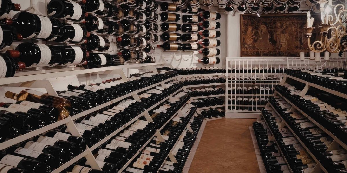A very large wine cellar, with rows full of wine bottles and large display bottles on the walls and ceiling.