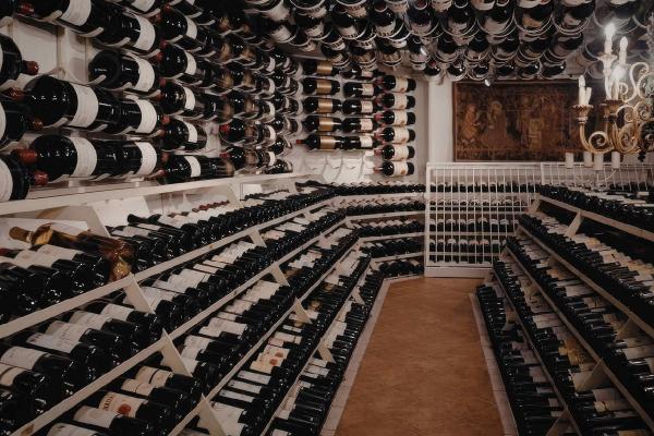 A very large wine cellar, with rows full of wine bottles and large display bottles on the walls and ceiling.