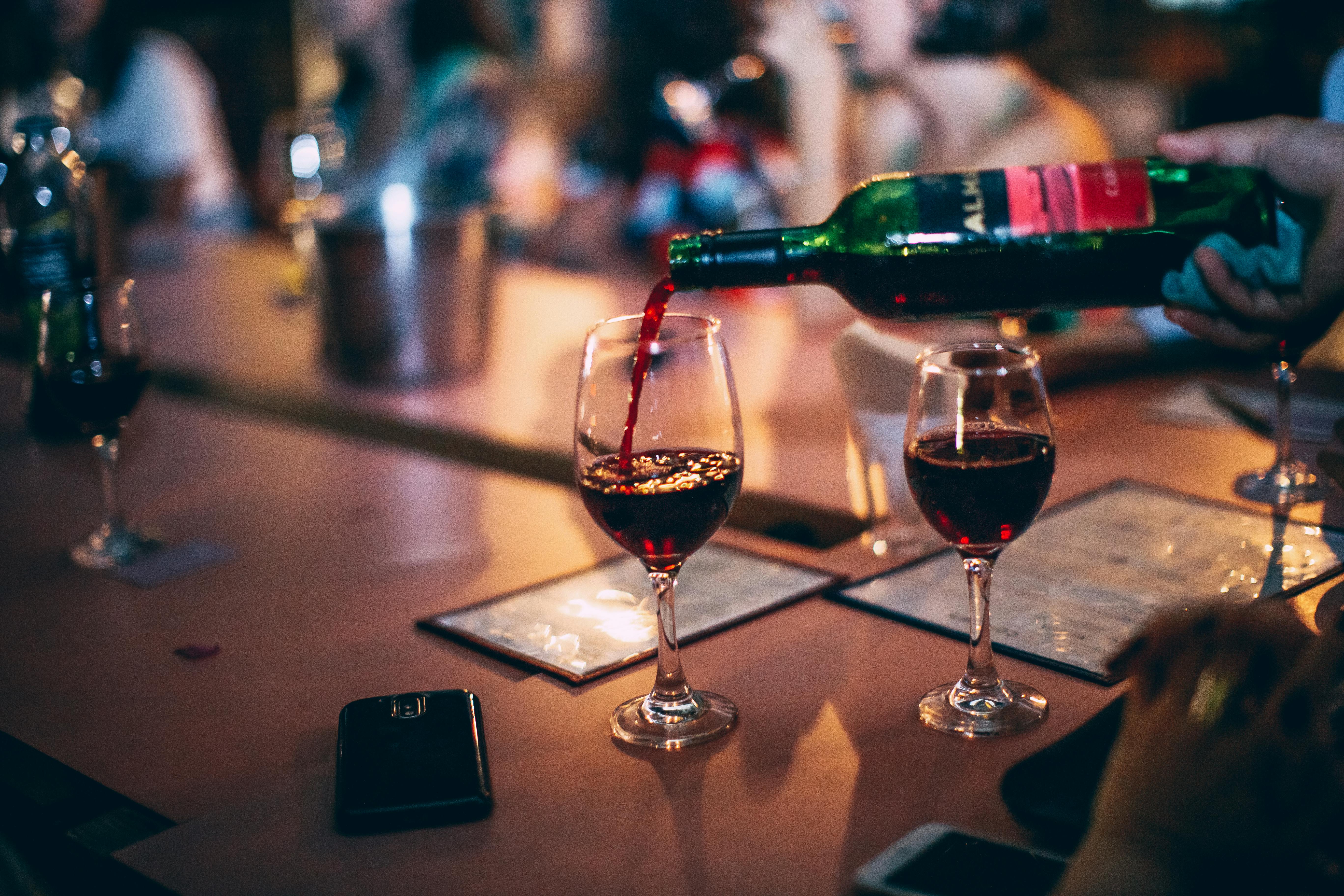 Two glasses of red wine resting on a table at a restaurant.