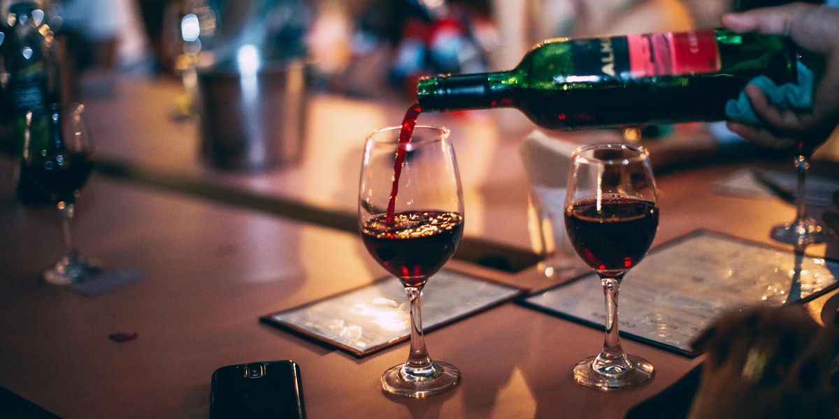 Two glasses of red wine resting on a table at a restaurant.
