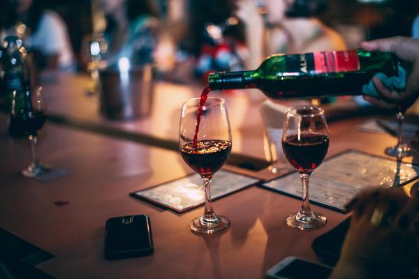 Two glasses of red wine resting on a table at a restaurant.