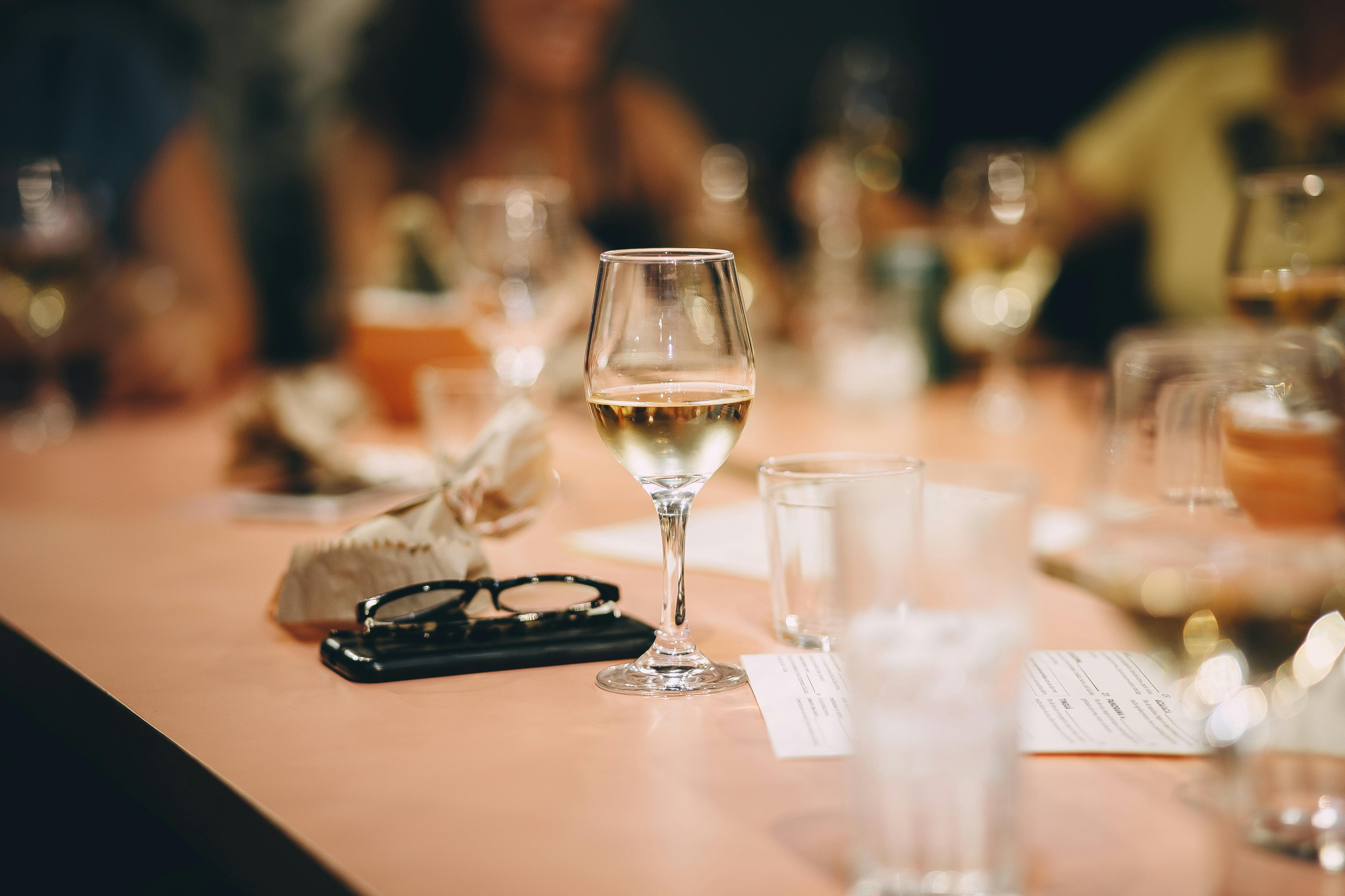 Wine glasses, water glasses, and other miscellaneous items fill a table at a restaurant.