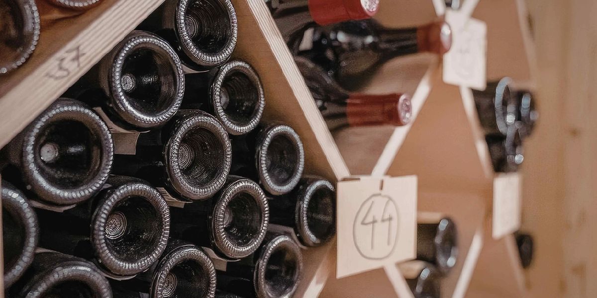 A stack of red wine bottles occupy a shelf in a wine shop.