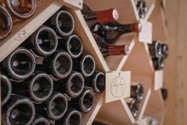 A stack of red wine bottles occupy a shelf in a wine shop.