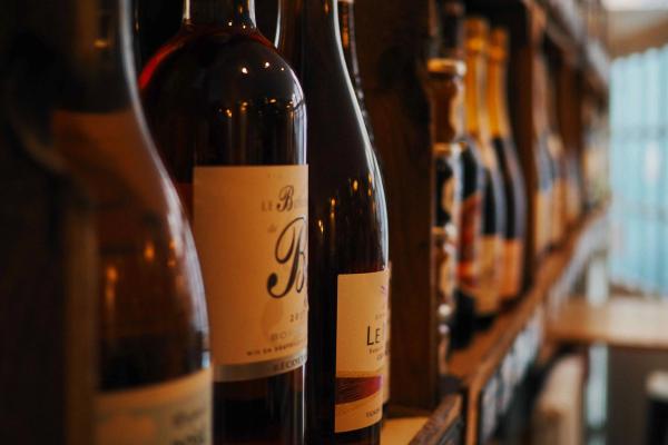 Close-up of wine bottles lined up on a wooden rack with labels facing forward.