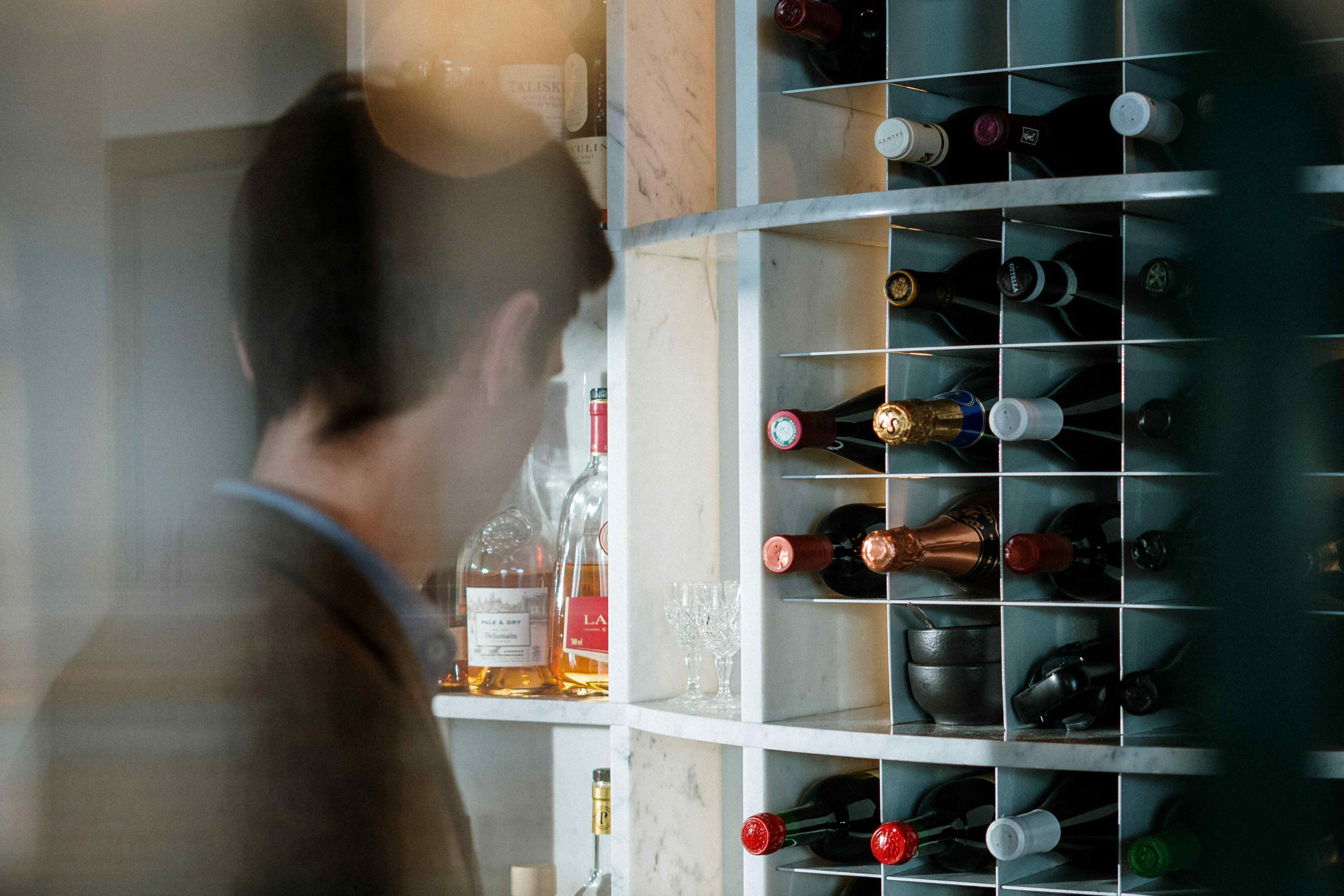 A collector browsing a wine rack with bottles stored in a modern built-in wine storage unit.