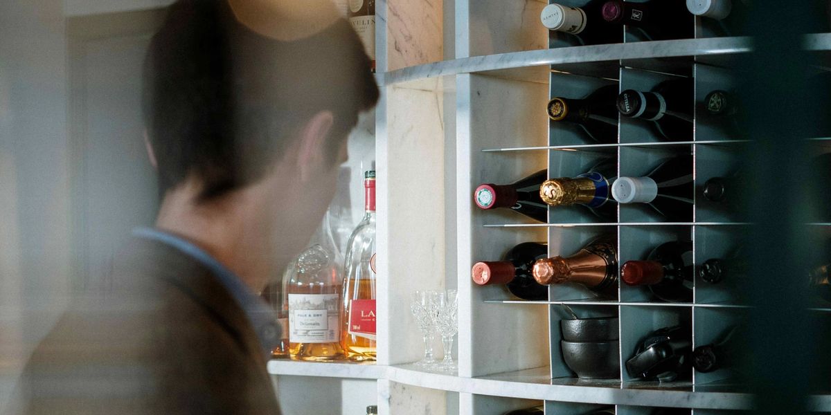 A collector browsing a wine rack with bottles stored in a modern built-in wine storage unit.