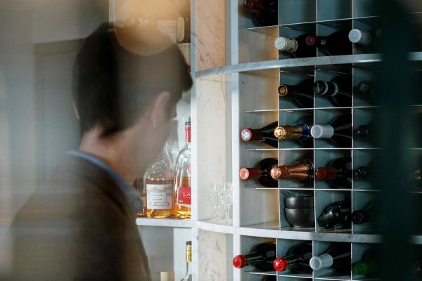 A collector browsing a wine rack with bottles stored in a modern built-in wine storage unit.