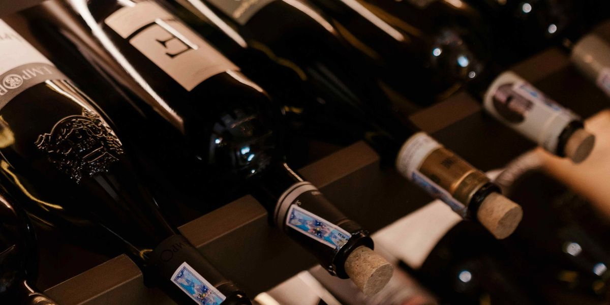 Wine bottles stored horizontally on cellar racks showing corks and labels up close.