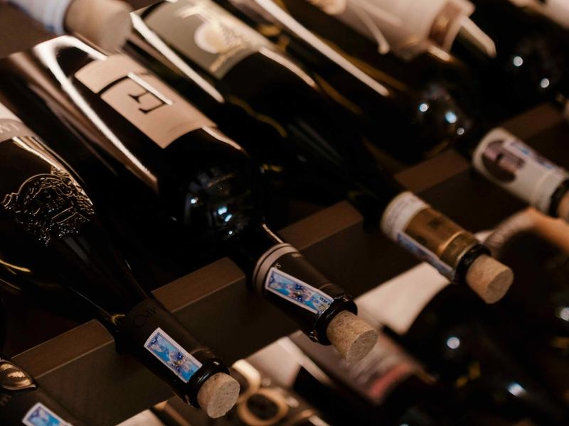 Wine bottles stored horizontally on cellar racks showing corks and labels up close.