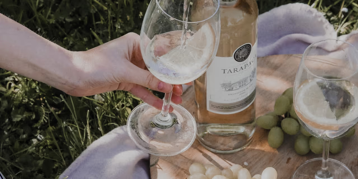 White wine is poured into a wine glass at a picnic.