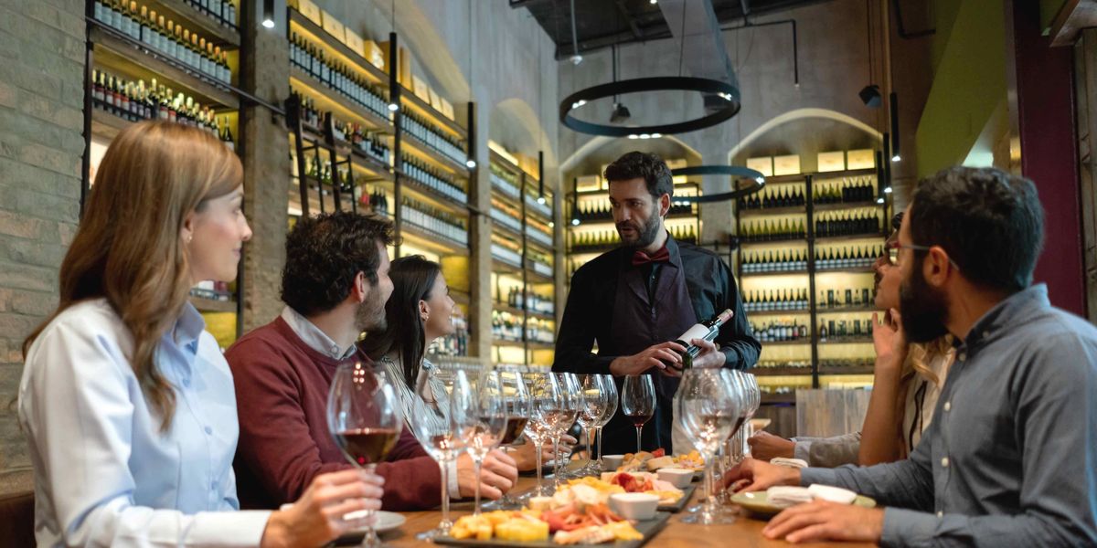 A sommelier guiding a group of people through a wine tasting at a restaurant.