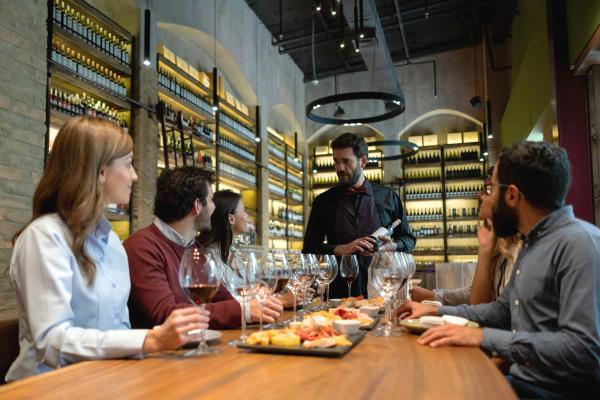 A sommelier guiding a group of people through a wine tasting at a restaurant.