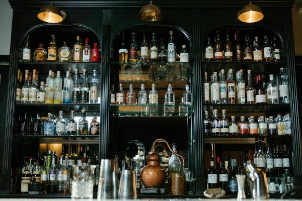 Display shelves behind a restaurant's bar, full of wine and liquor bottles.