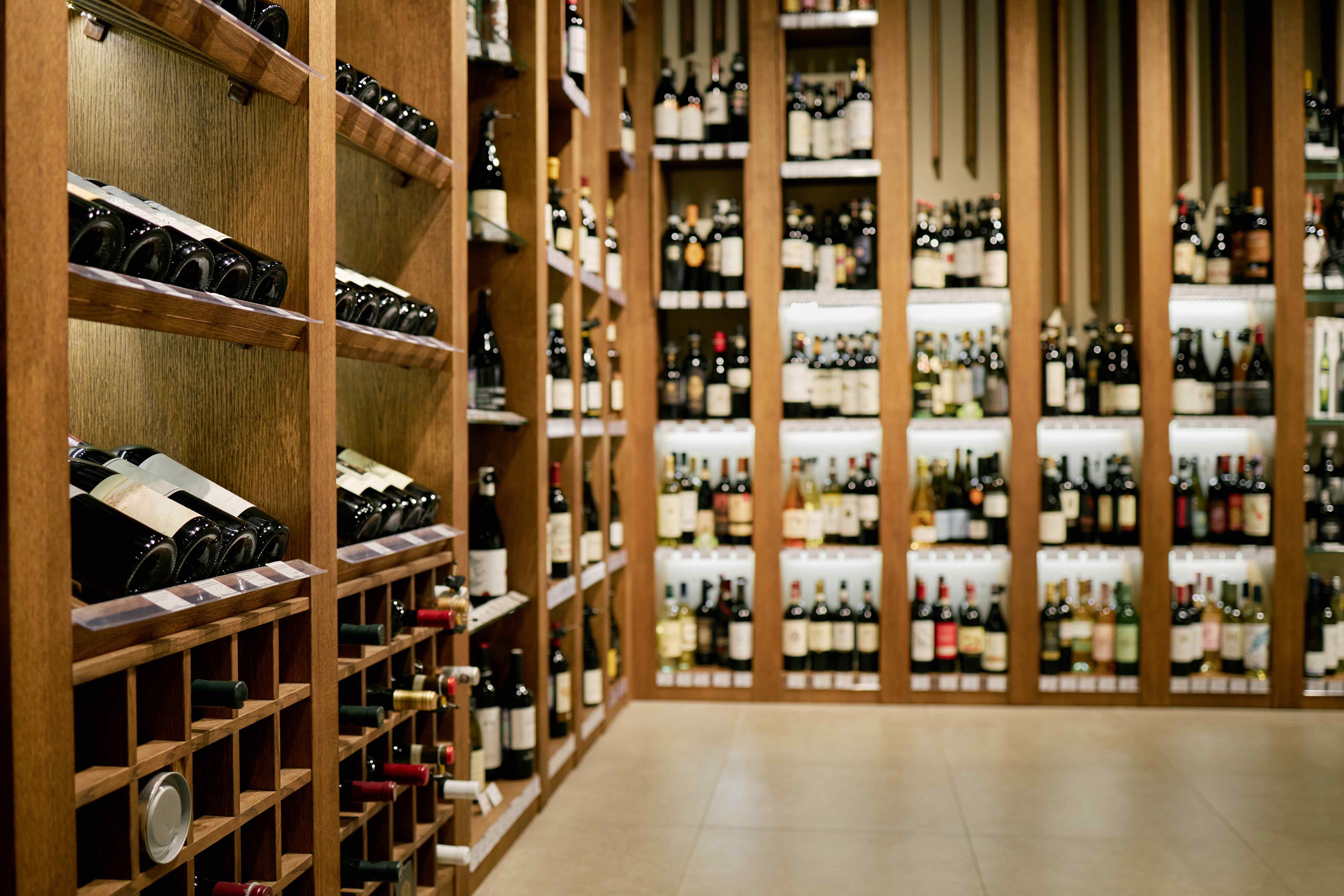 Wooden wine racks filled with bottles lining a long cellar aisle.