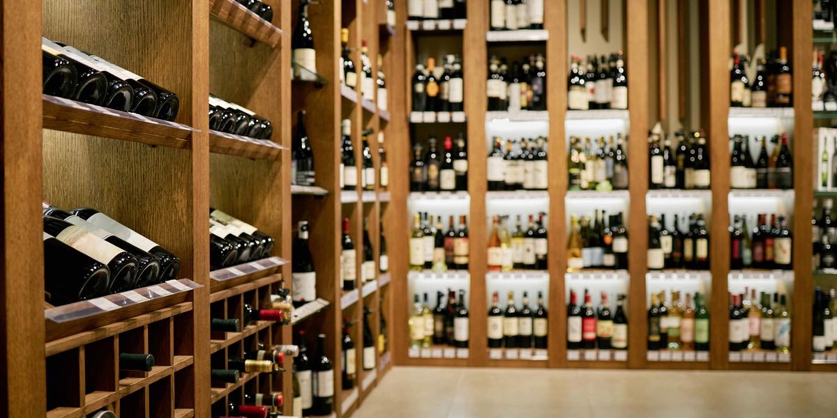 Wooden wine racks filled with bottles lining a long cellar aisle.