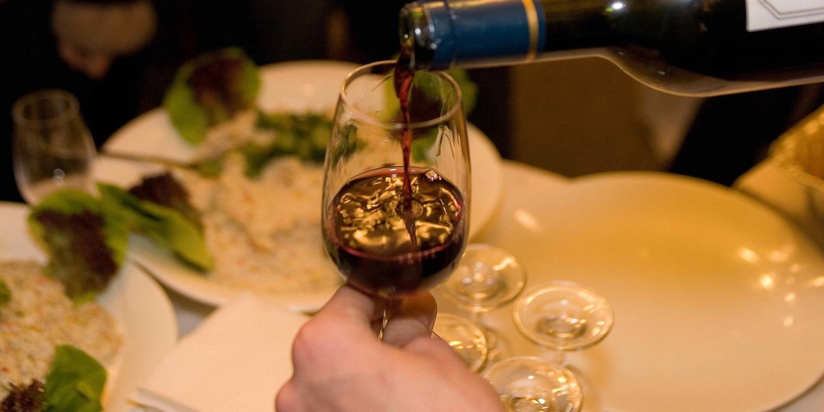 A wine glass being filled with red wine at a restaurant.