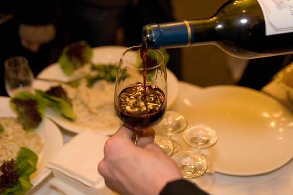 A wine glass being filled with red wine at a restaurant.