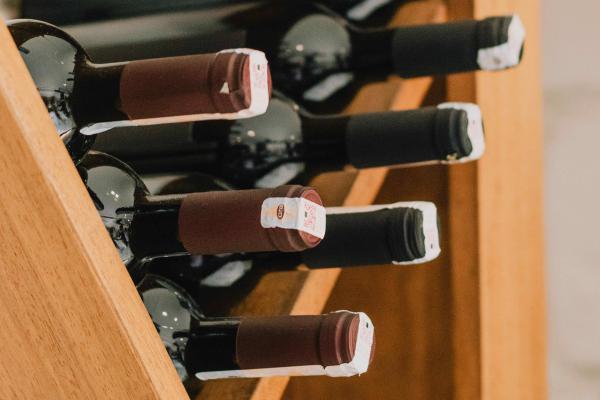 Red wine bottles fill a shelf in a wine cellar.