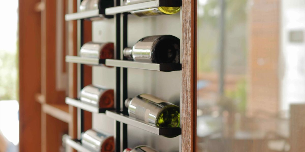 A modern wall-mounted metal wine rack displaying bottles horizontally in a contemporary space.