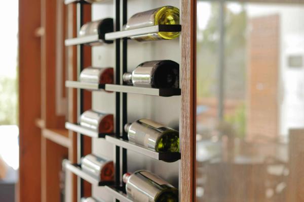 A modern wall-mounted metal wine rack displaying bottles horizontally in a contemporary space.