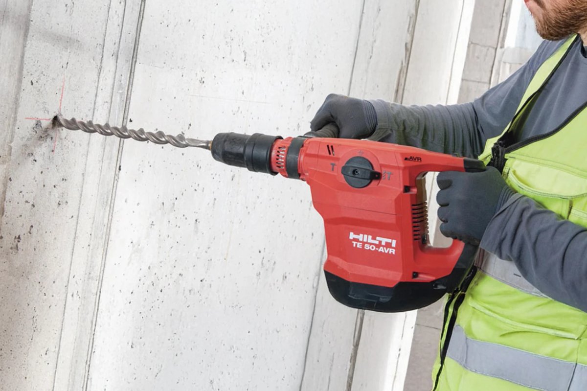 A worker in a hi-vis vest drilling into a concrete wall with a red Hilti TE 50-AVR rotary hammer drill