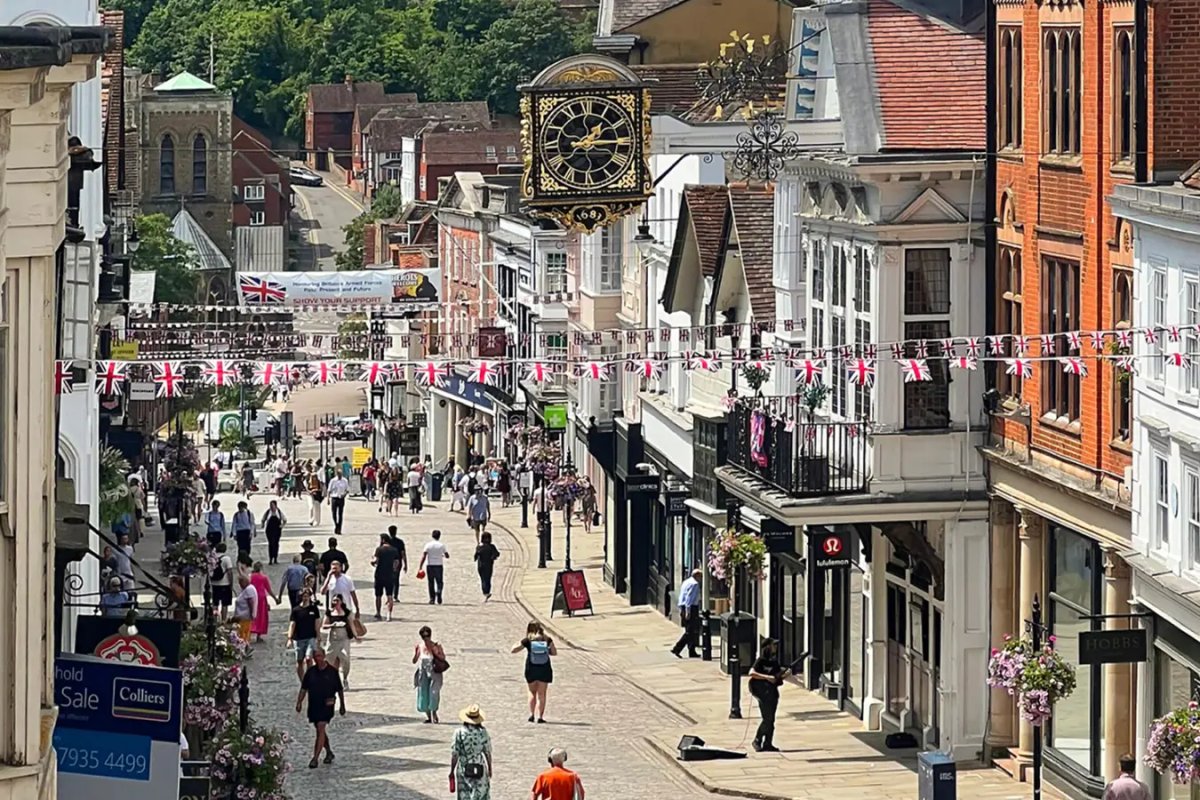 Photograph from above looking down Guildford High Street with bunting and flags being displayed between the shops