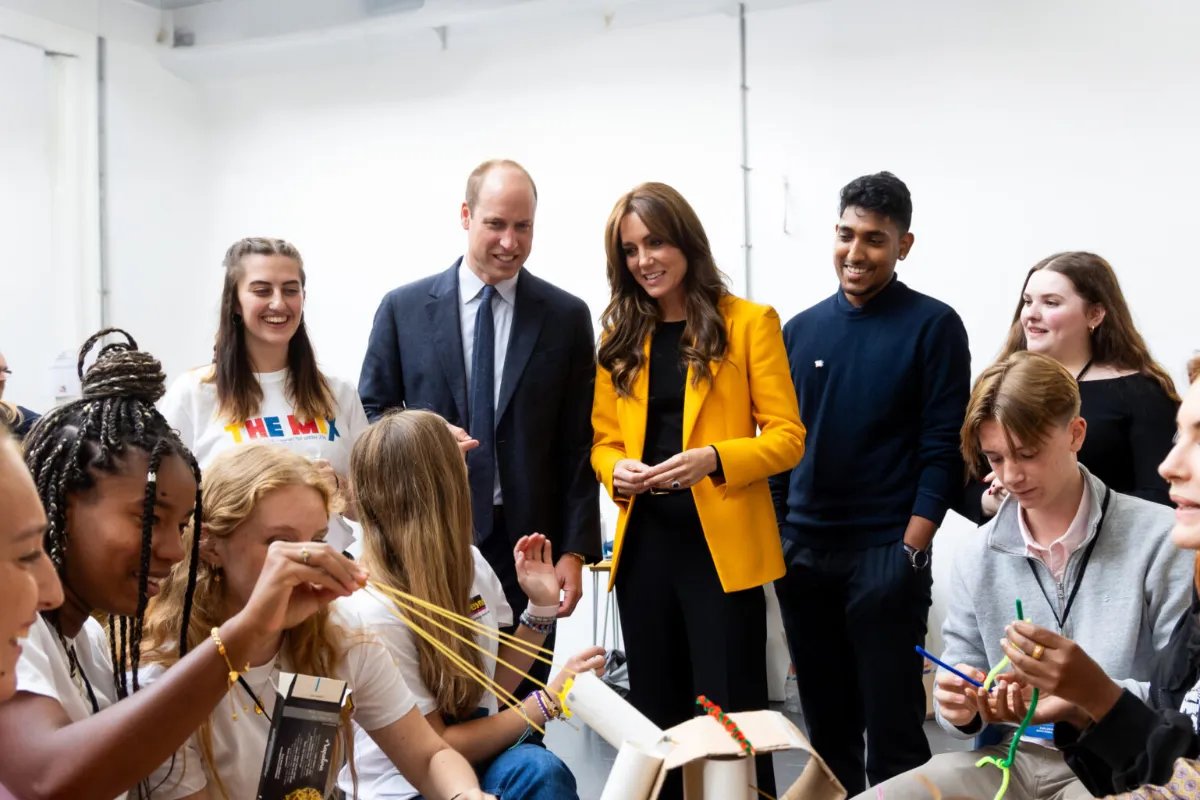 Photograph of Prince William and Princess Kate in a room with young people having conversation