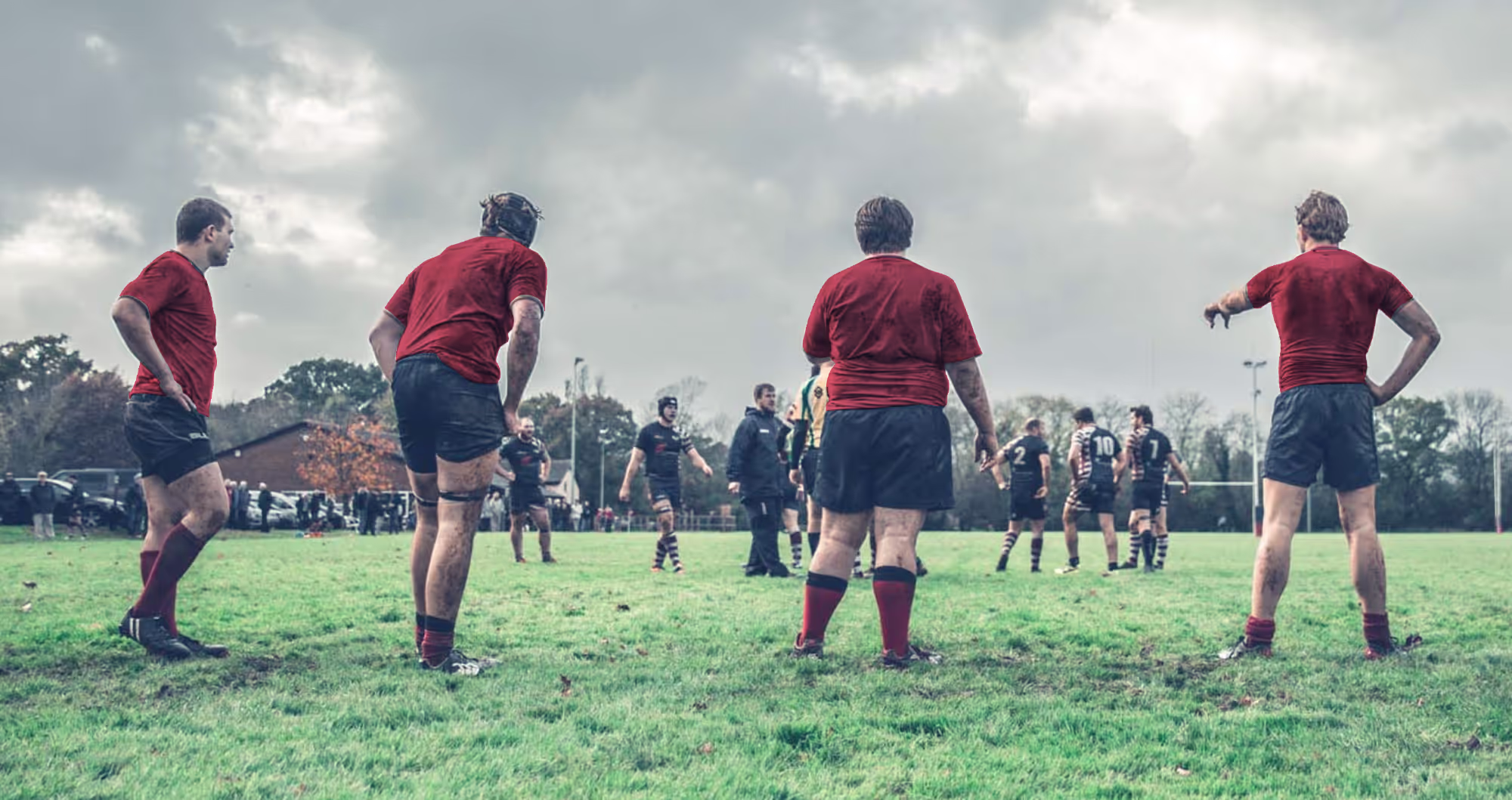 4 Men stood in a line playing rugby