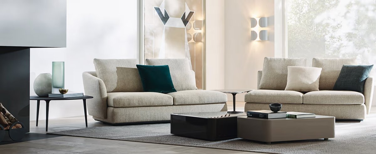 Two cream upholstered sofas with patterned cushions arranged around dark coffee tables in a bright living room