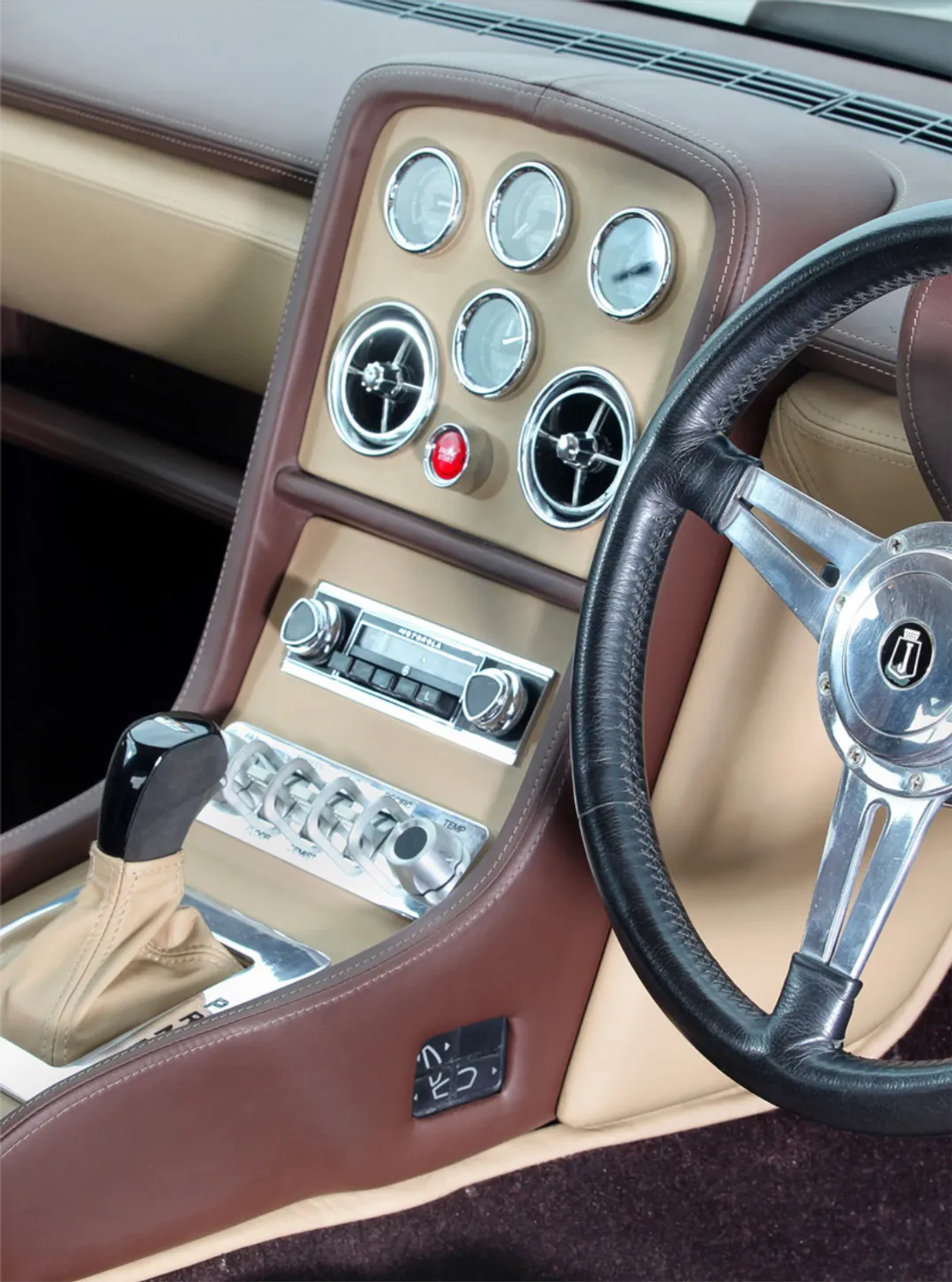 Close-up of a Jensen Interceptor's interior dashboard with gauge cluster, leather trim, and steering wheel