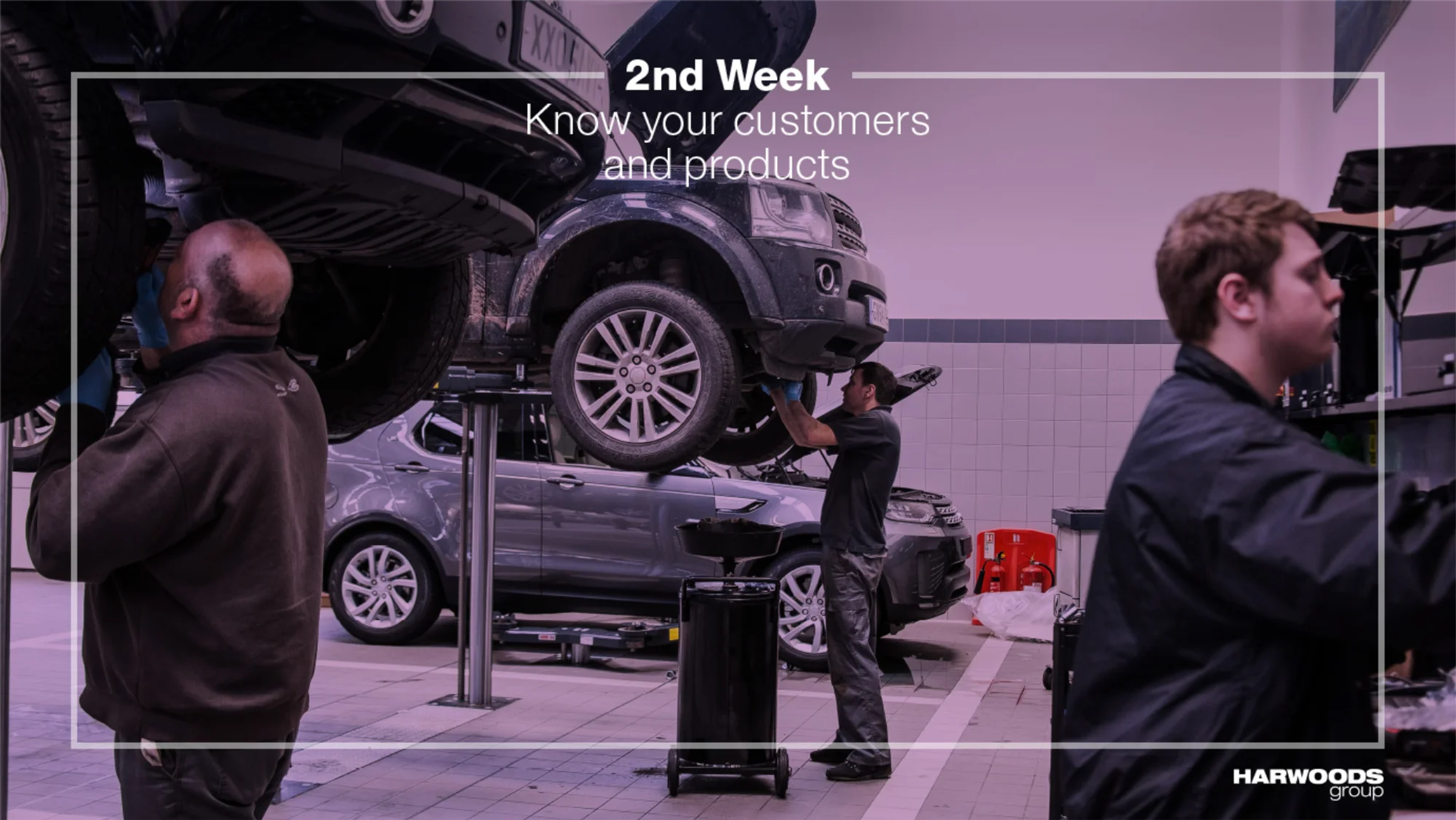 Two colleagues reviewing diagnostics on a laptop beside a car on a ramp, with '1st Day: Finding your way around' overlay text